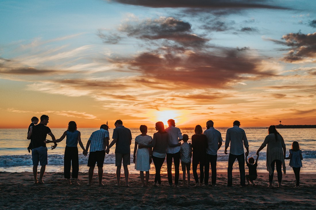 Familie genießt gemeinsam den Sonnenuntergang am Meer